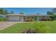 Inviting single-story home featuring lush green lawn, colorful flowerbeds, and a bright green front door at 1857 Jasmine Dr, Sarasota, FL 34239