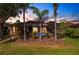 Backyard featuring a screened-in patio with a pool, surrounded by palm trees and lush landscaping at 235 Dahlia Ct, Bradenton, FL 34212