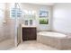 Elegant bathroom featuring a glass shower, soaking tub, and dark wood vanity with a view to the outside at 235 Dahlia Ct, Bradenton, FL 34212