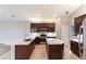 Modern kitchen featuring dark wood cabinets, stainless steel appliances, island, and tile flooring at 235 Dahlia Ct, Bradenton, FL 34212