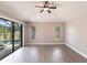Bright, spacious living room with wood flooring, a ceiling fan, and sliding glass doors that open to the pool area at 235 Dahlia Ct, Bradenton, FL 34212