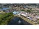 Aerial view of a community clubhouse with a pool, tennis courts, and lush landscaping near a serene lake at 2407 New Haven Cir, Sun City Center, FL 33573