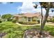 Well-maintained single-story home with lush green lawn, mature shrubs, and a brick-paved walkway at 2407 New Haven Cir, Sun City Center, FL 33573