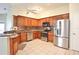 Modern kitchen with stainless steel appliances, wood cabinetry, and tiled flooring for easy maintenance at 2407 New Haven Cir, Sun City Center, FL 33573