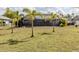 Large backyard featuring lush lawn, palm trees, and a screened-in pool area at 245 Woodingham Trl, Venice, FL 34292