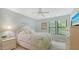Bright bedroom with white furniture, ceiling fan and view of lush landscaping at 4009 Crockers Lake Blvd # 22, Sarasota, FL 34238