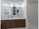 Bright bathroom featuring a double sink vanity with white countertop, dark wood cabinets and a glass shower door at 4435 Beauchamp Ct, Sarasota, FL 34243