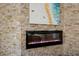 Close-up of a modern fireplace set in a stone accent wall with a beach painting above at 4435 Beauchamp Ct, Sarasota, FL 34243