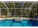 Stunning in-ground pool with attached spa surrounded by a screened enclosure and mature trees at 4435 Beauchamp Ct, Sarasota, FL 34243