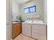 Bright laundry room with a sink, counter, storage shelf, window, and washer-dryer units at 4579 Tuscana Dr, Sarasota, FL 34241