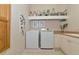 Bright laundry room with white front-loading washer and dryer with cabinets and shelf for storage and decor at 4700 Mainsail Dr, Bradenton, FL 34208