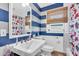 Nautical themed bathroom offers sink with mirror and cabinet, with a red floral shower curtain and blinds in the window at 5012 Eastchester Dr, Sarasota, FL 34234
