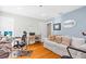 Bright living room features hardwood floors, white sofa, work space, and light blue accent wall at 5012 Eastchester Dr, Sarasota, FL 34234