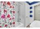 Bright tiled shower with floral shower curtain, white door, and blue and white striped accent wall at 5012 Eastchester Dr, Sarasota, FL 34234