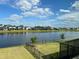 View of the backyard featuring a serene lake, a secure fence, and picturesque community homes at 5521 Summit Gln, Bradenton, FL 34203