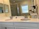 Bathroom featuring a double vanity with a white countertop, framed mirror, a window and tiled floors at 5521 Summit Gln, Bradenton, FL 34203