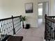 Carpeted hallway featuring dark wood railings, neutral walls and natural lighting leading to a bedroom at 5521 Summit Gln, Bradenton, FL 34203