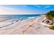 Beautiful aerial view of a sandy beach with clear blue water, a tiki hut and beach chairs at 6012 11Th W Ave, Bradenton, FL 34209