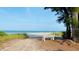 A bench faces the ocean on a quiet, sandy beach, with dune grass and trees nearby at 6012 11Th W Ave, Bradenton, FL 34209