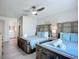 Bright bedroom featuring two cozy beds with stylish headboards, soft blue accents, and a ceiling fan at 6012 11Th W Ave, Bradenton, FL 34209
