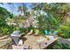 Spacious backyard featuring a grill, patio furniture, and lush greenery, perfect for outdoor entertaining at 620 Burke Rd, Venice, FL 34293