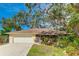 Front exterior view of the home featuring a well-manicured lawn, mature trees, and inviting curb appeal at 620 Burke Rd, Venice, FL 34293
