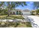 Attractive single-story home with a manicured lawn, two-car garage, complemented by mature trees and a colorful front door at 6617 Cheswick St, Sarasota, FL 34243