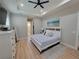 Bright main bedroom featuring a tray ceiling, ceiling fan, light wood floors, and a white wood bed frame at 6875 Beckwith Ave, North Port, FL 34291