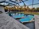 Luxurious screened-in pool area with in-pool loungers, chairs, a hot tub, and beautiful landscaping at 6875 Beckwith Ave, North Port, FL 34291