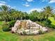 Scenic entrance with a stone waterfall and landscaping, showcasing the community's welcoming ambiance at 7019 River Hammock Dr # 306, Bradenton, FL 34212