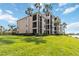 Beautiful exterior shot of a multi-story condo building with screened balconies, nestled amidst a manicured lawn and palm trees at 7019 River Hammock Dr # 306, Bradenton, FL 34212