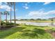 Scenic view of a lush green golf course and tranquil lake, framed by swaying palm trees on a sunny day at 7019 River Hammock Dr # 306, Bradenton, FL 34212