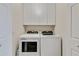 Efficient laundry room with a side-by-side washer and dryer, and white cabinets at 7019 River Hammock Dr # 306, Bradenton, FL 34212