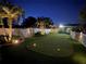 Backyard putting green surrounded by white picket fence, palm trees and landscape lighting at 7508 9Th N Ave, St Petersburg, FL 33710