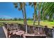 Outdoor deck features comfortable Adirondack chairs with a view of lush green lawns and swaying palm trees at 7728 Club Ln, Sarasota, FL 34238