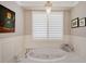 Bright bathroom featuring a soaking tub under a window, accented by a charming chandelier at 7728 Club Ln, Sarasota, FL 34238