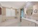 Luxurious bathroom with soaking tub, shuttered window, and white marble countertop with vanity at 7728 Club Ln, Sarasota, FL 34238