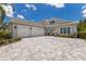Beautiful home exterior featuring a three-car garage, gray brick driveway, and lush landscaping at 8133 Grande Shores Dr, Sarasota, FL 34240