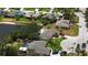 A home near a lake features mature landscaping, circular driveway with a red car, and a neighboring screened pool at 8808 44Th Avenue W Dr, Bradenton, FL 34210