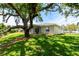The rear exterior of the home has a well-manicured lawn with a large tree, landscaping and screened-in porch at 8808 44Th Avenue W Dr, Bradenton, FL 34210