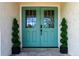 Inviting double front doors in light blue, framed by symmetrical spiral topiaries and stone-tiled entryway at 8808 44Th Avenue W Dr, Bradenton, FL 34210