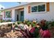 A close-up of the blue front door, wooden shutters, and well-maintained garden with colorful plants at 8808 44Th Avenue W Dr, Bradenton, FL 34210