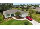 Charming single-story home featuring a lush lawn, a paver walkway, and a red sports car in the driveway at 8808 44Th Avenue W Dr, Bradenton, FL 34210