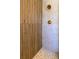 Close up of modern shower with wood wall accent, pebble floor and gold fixtures at 8808 44Th Avenue W Dr, Bradenton, FL 34210
