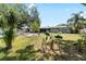 A large yard with trees and plantings surrounds the back of the home at 10827 Village Green Ave, Seminole, FL 33772