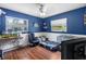Bright bedroom with blue walls, wood floors, two windows, a ceiling fan, and plenty of natural light at 10827 Village Green Ave, Seminole, FL 33772