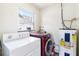 Functional laundry room featuring a modern washer and dryer with a water heater and natural light at 10827 Village Green Ave, Seminole, FL 33772