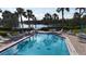 Community pool surrounded by palm trees and overlooking a scenic lake at 111 Whispering Sands Cir # V38, Sarasota, FL 34242