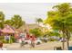 A sunny Siesta Key Village street view featuring colorful shops, lush trees, and people enjoying a bike ride at 111 Whispering Sands Cir # V38, Sarasota, FL 34242