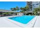 Sparkling community pool surrounded by palms, lounge chairs, and a covered patio at this lovely property at 1159 Lake House Cir # C120, Sarasota, FL 34242